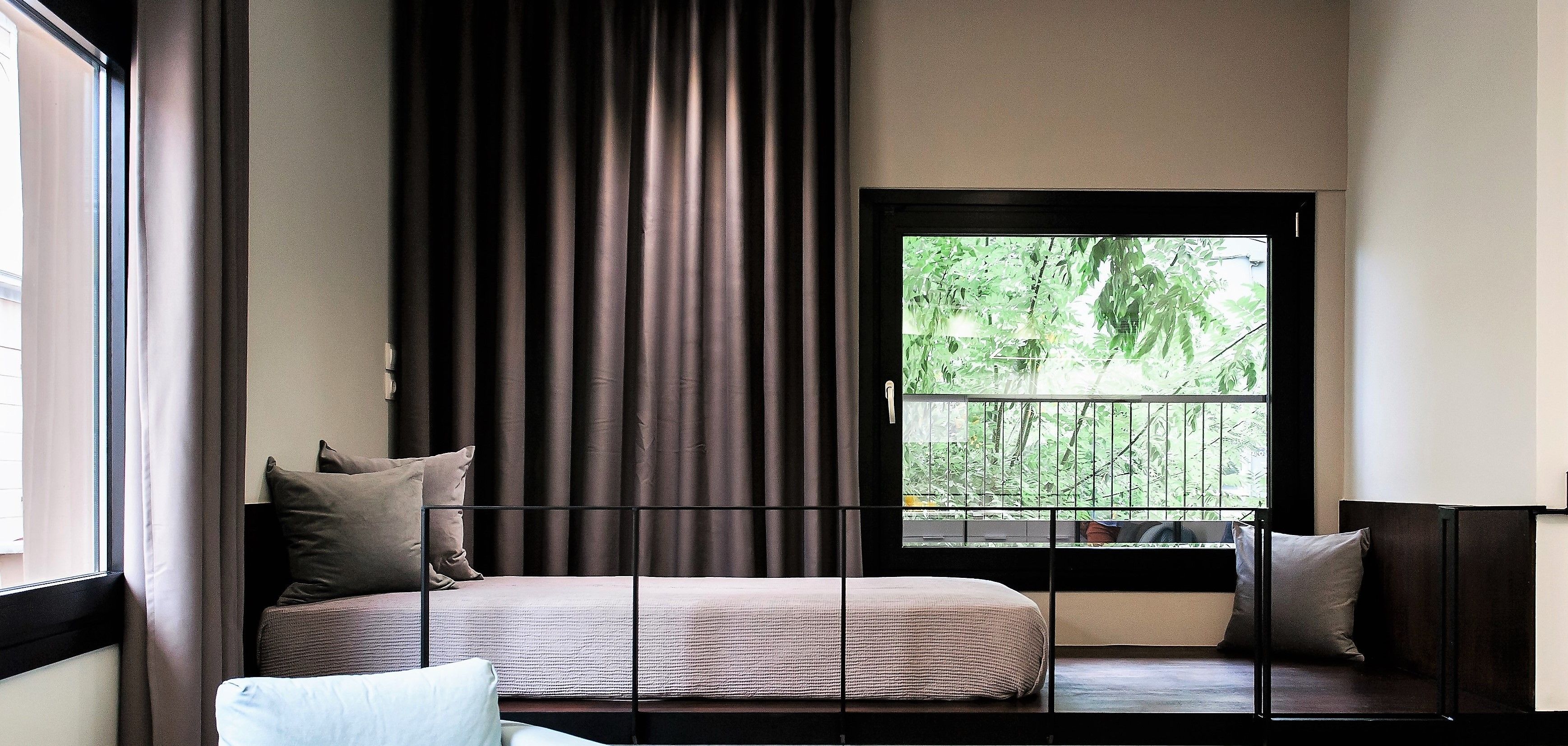 A modern bedroom with a large window, a bed, and a seating area.
