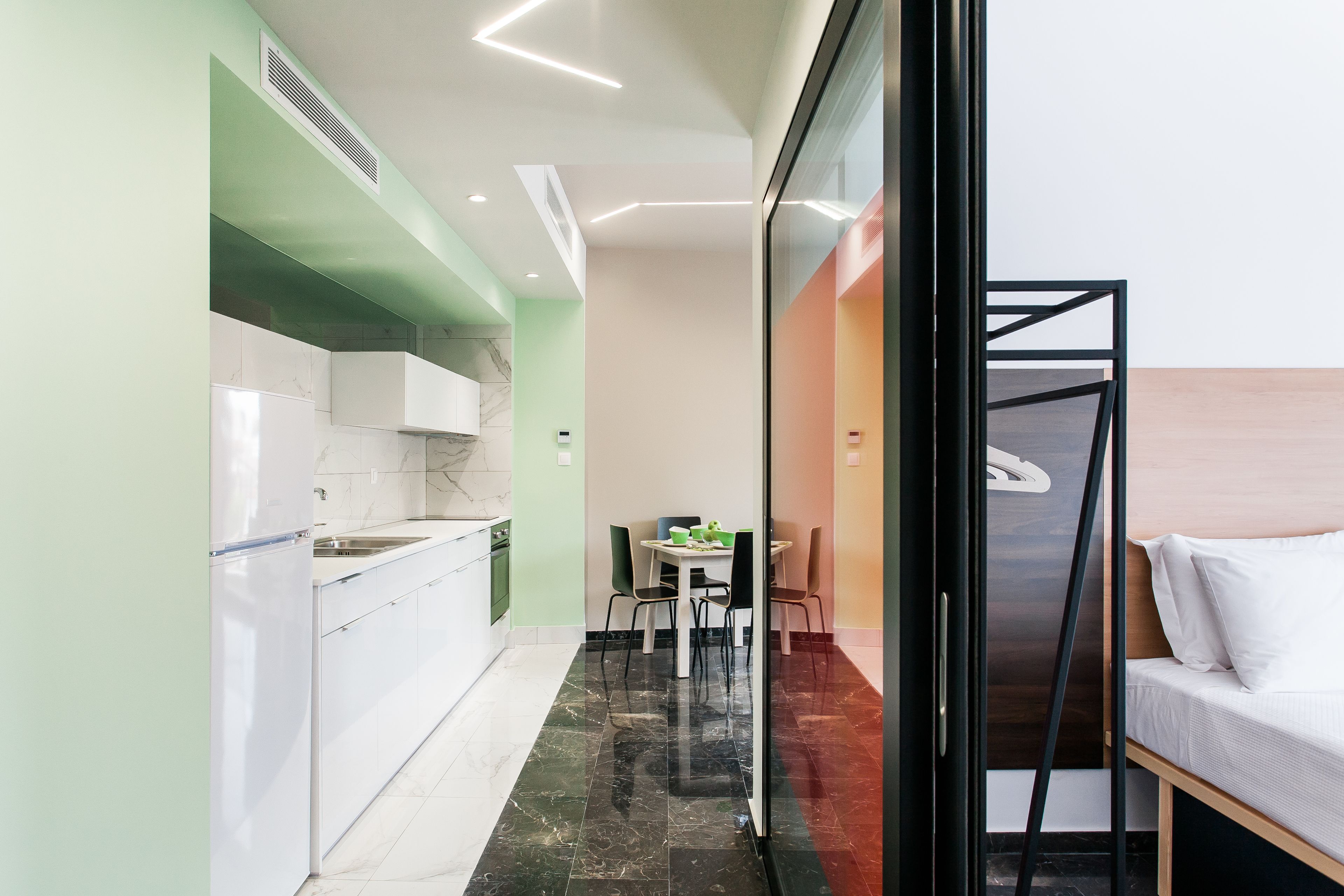 A modern kitchen with white cabinets, a marble backsplash, and a dining area with a table and chairs.