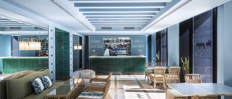 A modern interior with a bar area, seating arrangements, and a green accent wall.