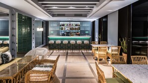 A bar area with a green-lit bar counter, wicker furniture, and a seating area with a marble table. - Intelier Casa de Indias Hotel by Intelier Hotels & Suites (Seville)