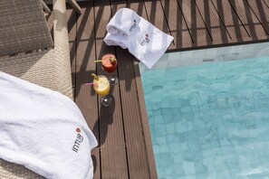 A wooden deck with a pool, two towels, and two drinks. - Intelier Casa de Indias Hotel by Intelier Hotels & Suites (Seville)