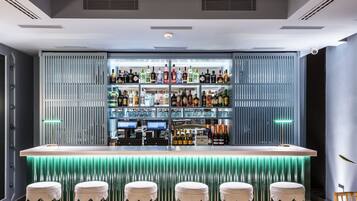 Eine moderne Bar mit einer zentralen Theke, mehreren Barhocker und einer Auswahl an Spirituosenflaschen.