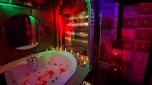 Un baño moderno con una bañera grande, un espejo y una pared con textura.