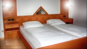 A double bed with wooden headboard and footboard, two bedside tables, and a mirror above the bed. - Hotel Anker (Linden)