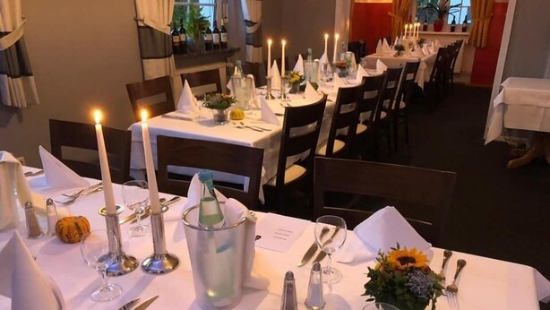 A well-set dining table with candles, cutlery, and a centerpiece. - Hotel Anker (Linden)