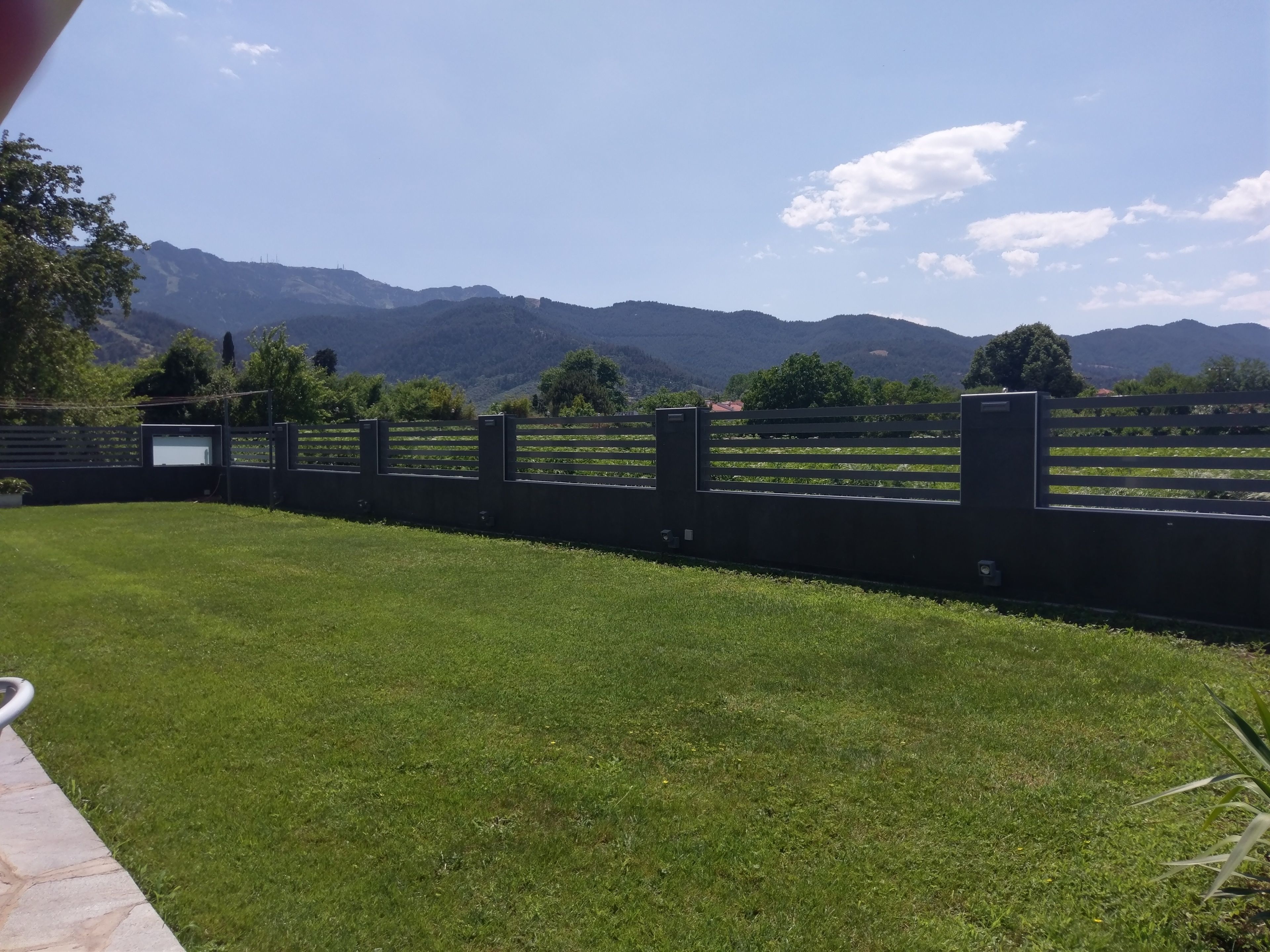 A grassy area with a fence and mountains in the background.