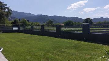 A grassy area with a fence and mountains in the background.