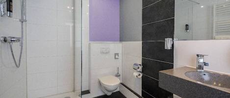 Un baño moderno con cabina de ducha de vidrio, un inodoro y un lavabo con espejo.