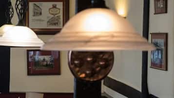 Un pasillo con cuadros enmarcados en las paredes y una lámpara con un pie decorativo.