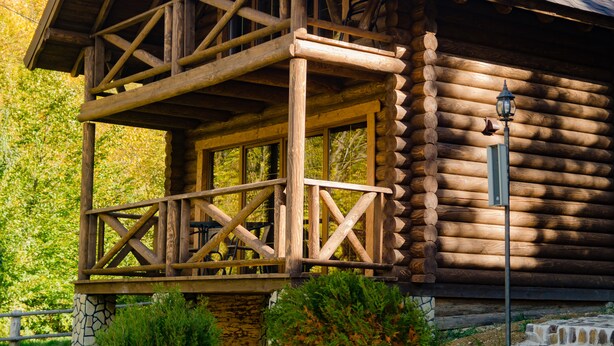 A log cabin with a wooden balcony and a stone foundation. - Monastic-SPA (Oriv)