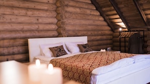 A log cabin-style bedroom with a wooden headboard, patterned bedding, and a hanging clothes rack. - Monastic-SPA (Oriv)