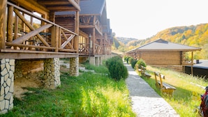 A wooden cabin with a stone foundation, a stone pathway, and a bench. - Monastic-SPA (Oriv)