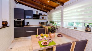 Una cucina moderna con mobili scuri, soffitto in legno e zona pranzo con tavolo apparecchiato per la colazione.