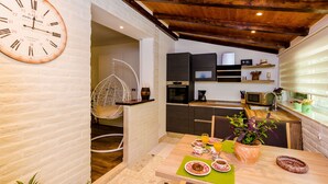 Una cucina moderna con soffitto in legno, una poltrona sospesa e un'area pranzo con la tavola apparecchiata per la colazione.