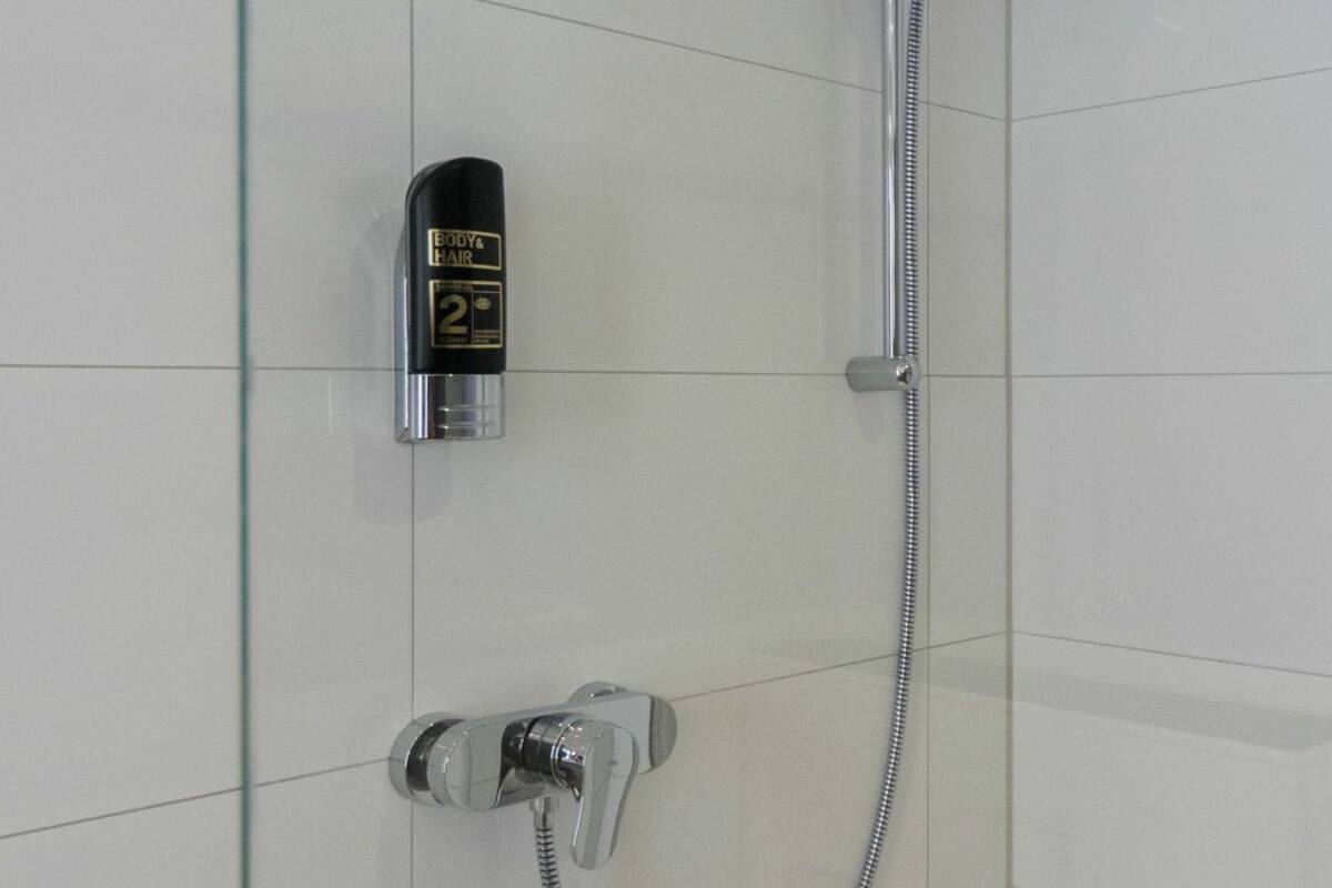 A shower with a handheld spray bottle and a handheld showerhead.