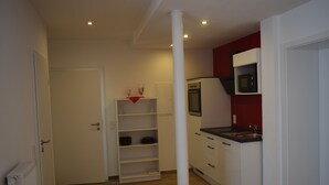A compact kitchen with white cabinets, a microwave, and a wooden floor. - Hotel Holländischer Hof (Lich)