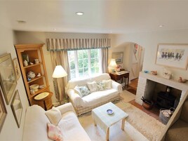 A cozy living room with a sofa, a small table, a bookshelf, and a fireplace.