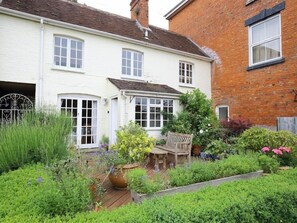 A two-story house with a garden in front. - The Mews Cottage (Salisbury)