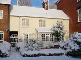 Una casa de dos plantas con techo nevado y un invernadero.