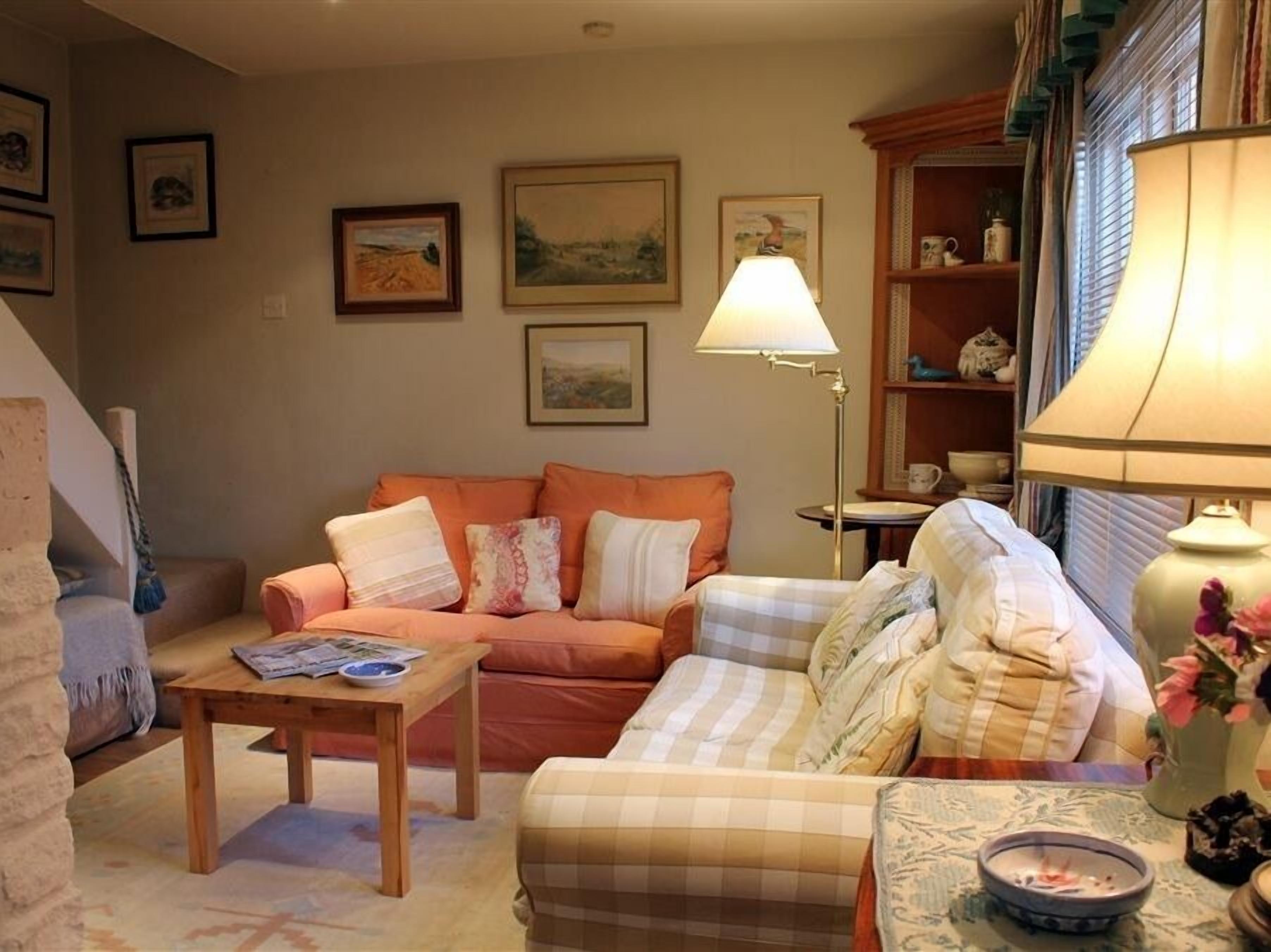 A cozy living room with a sofa, a smaller couch, a coffee table, and a lamp.
