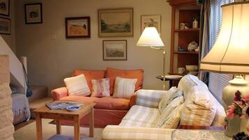 A cozy living room with a sofa, a smaller couch, a coffee table, and a lamp.