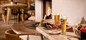 A wooden table with a beer mug, a glass of beer, and a charcuterie board with meats and olives. - Alpenchalet Zum-Jeremia (Grainau)