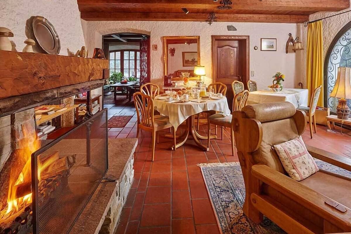 Ein gemütlicher Essbereich mit Kamin, Holzmöbeln und Blick auf den Speisesaal.