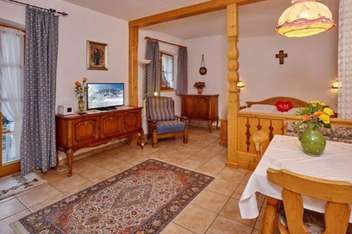 Ein gemütliches Wohnzimmer mit Fernseher, einem Holztisch und einem gemusterten Teppich.