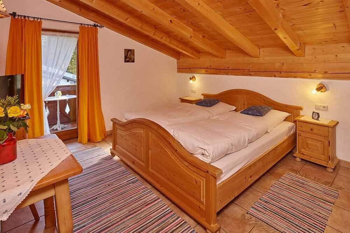 Ein schlafzimmer mit Holzrahmen, einem Bett, Nachttischen und einem kleinen Tisch mit Blumen in einer Vase.