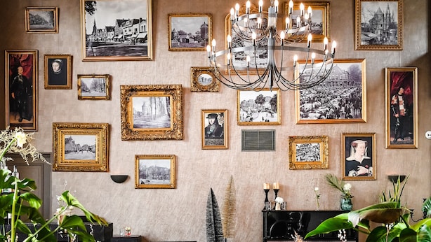 A dining area with a chandelier, framed pictures on the wall, and a black piano. - Fletcher Slothotel Schagen (Schagen)