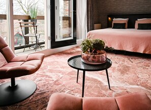 A modern bedroom with a bed, a chair, a small table with a plant, and a view of the outside. - Fletcher Slothotel Schagen (Schagen)