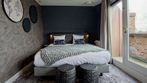 A modern bedroom with a large bed, two bedside tables, a headboard, and a view through a glass door. - Fletcher Slothotel Schagen (Schagen)