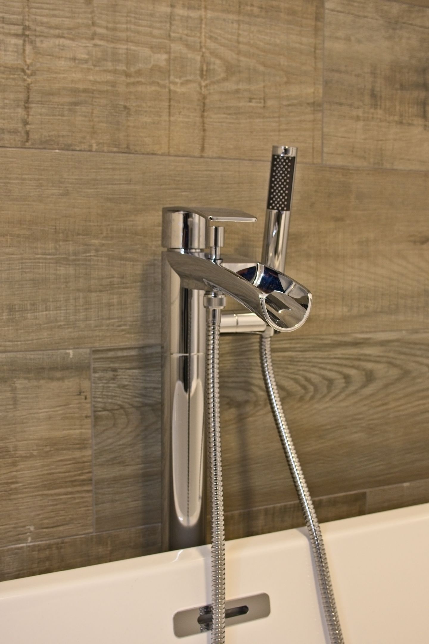 A chrome showerhead with a handheld shower attachment, mounted on a tiled wall.