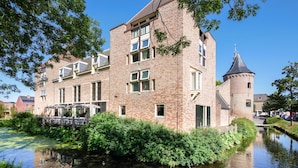 A historic building with a tower, a canal, and a bridge. - Fletcher Slothotel Schagen (Schagen)