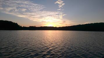 A calm lake at sunset with a forested shoreline.