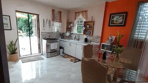 Une cuisine spacieuse avec un coin repas, dotée d’une grande fenêtre, d’un four encastré et d’une table à manger avec des chaises.