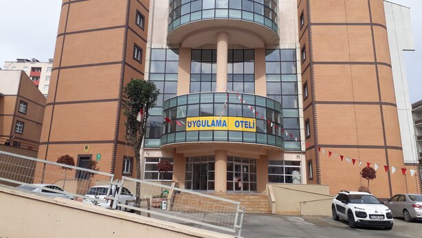 Ein Gebäude mit einer gewölbten Glasfassade und einem Schild mit der Aufschrift "UYGULAMA OTELİ".