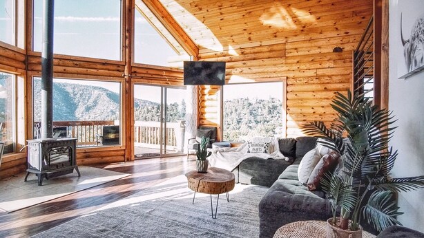Ein geräumiges Wohnzimmer mit einer großen Holzbalkendecke, Kamin, einer Couch und einem Fernseher.