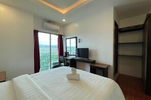 A hotel room with a bed, a desk, a TV, and a view of the outdoors. - Diamond Spring Hotel Angeles (Angeles City)