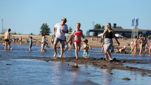 Eine Strandansicht mit Menschen, die im Sand spazieren und spielen.