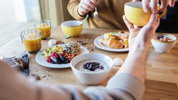 A breakfast setting with various dishes, including eggs, pastries, and a croissant, on a wooden table.