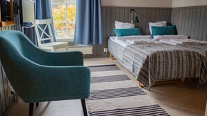 Ein Schlafzimmer mit Bett, Stuhl, Schreibtisch und einem Fenster mit Vorhängen.