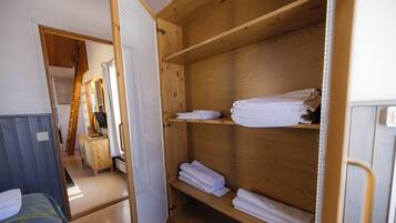 Una habitación con un armario de madera, una cama y un baño con puerta de madera.