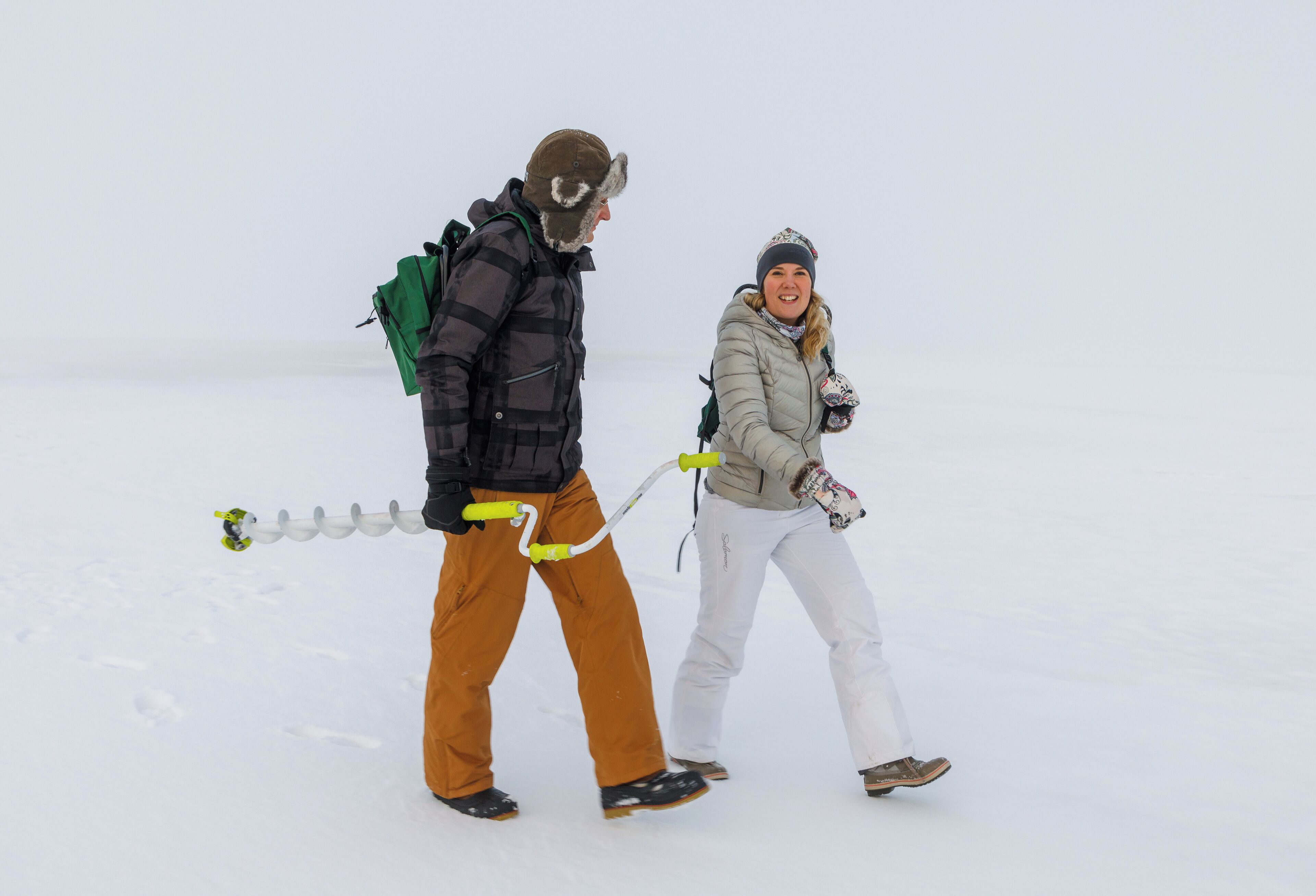 Two people walking on snow with a sled.