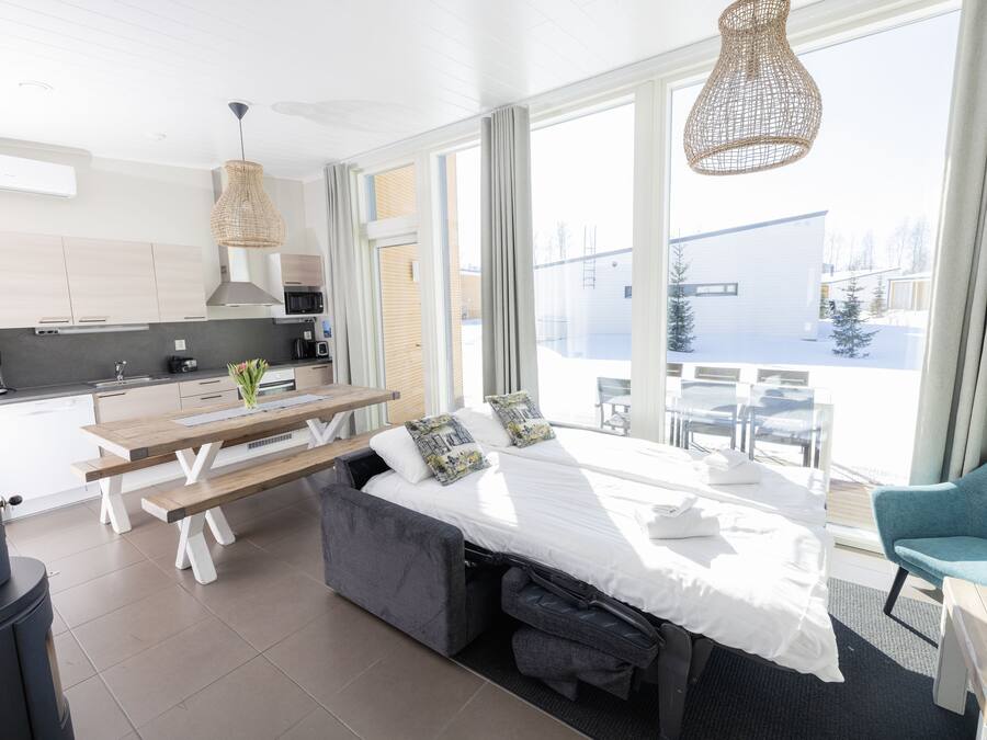 Una habitación de hotel moderna con cama, mesa de comedor y kitchenette.