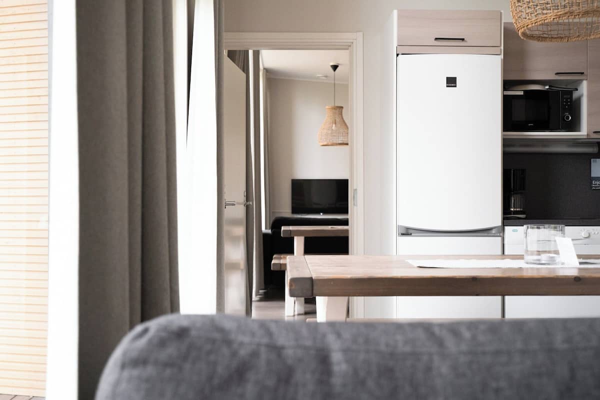 Una cocina moderna con refrigerador, microondas y comedor con mesa y sillas.