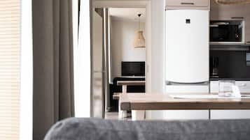 A modern kitchen with a refrigerator, microwave, and a dining area with a table and chairs.