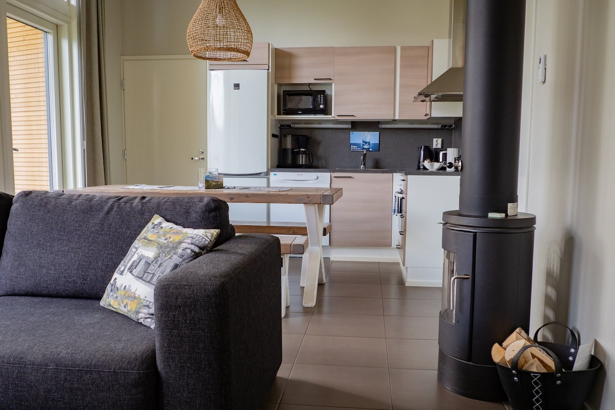 Una sala de estar moderna con un sofá, una mesa de comedor y una zona de cocina con estufa y microondas.