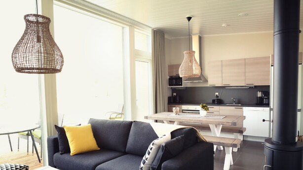 Ein modernes Wohnzimmer mit einer Couch, einem Esstisch und einer Küchenzeile im Hintergrund.