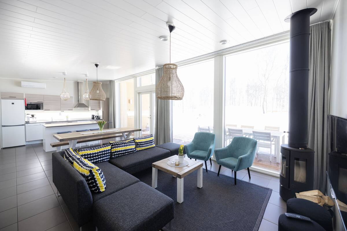 Una sala de estar moderna con un sofá seccional, dos sillones, una mesa de centro y una chimenea.